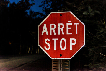 Security stop slow down sign at night in Canada Quebec, arret means stop in french