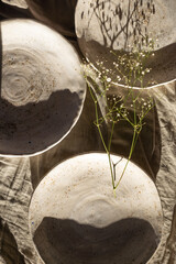 A beautiful composition of handmade plates and a branch of dry grass. Handmade, ceramics, stylish tableware for the home.