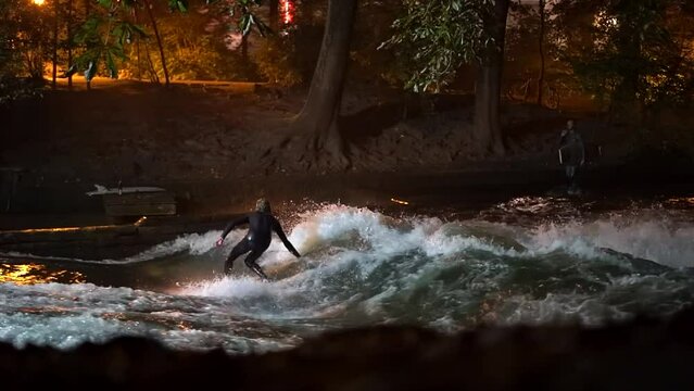 Cinematic fade slow motion Eisbach Wave River Surfer community Munich Germany ground level zoomed in fall autumn beautiful night surfing high flow water surf Upper Bavaria Alps flow follow movement