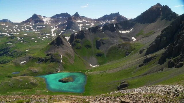 Aerial cinematic upper view  Ice Lake Basin Silverton Island Lake aqua blue clear water alpine tundra stunning mountain range snow wildflowers mid summer daytime beautiful slow pan to the right motion