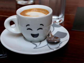cup of coffee on table with happy face on cup