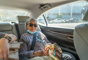 Senior woman travelling in the car. Sitting in the back seat of a car.