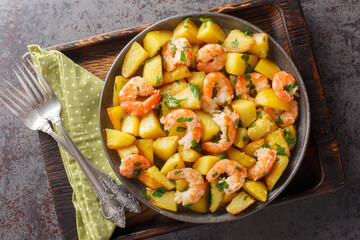 Spanish Potatoes roasted with Garlic Shrimp close-up in a plate on the table. Horizontal top view from above