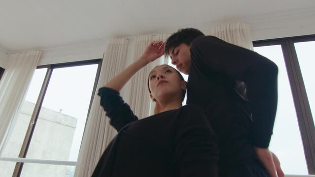 Couple of young talented dancers performing partner moves, choreographing contemporary dance together in a studio. Zoom shot