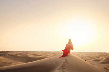 Fototapeta na wymiar Woman in sands dunes of desert at sunset