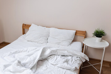 Unmade bed with white messy crumpled blanket, pillows and sheet. Mess in bedroom, cheap hotel or appartment room - obrazy, fototapety, plakaty