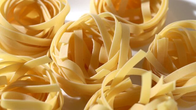 Close-up video of dried pasta placed on a white plate. Tagliatelle. rotation.