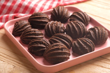 chocolate choux on a pink plate. Sweet pastry is made from wheat flour, eggs, chocolate, sugar. blurred image.