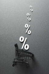Shopping trolley and white percent signs with copy space on grey background