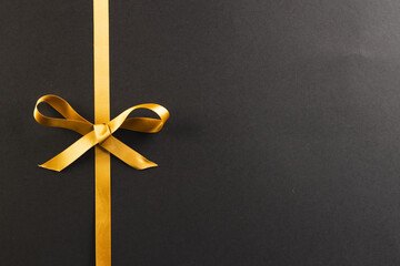 Gold gift ribbon and bow with copy space on black background