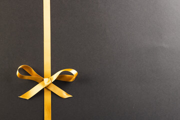 Gold gift ribbon and bow with copy space on black background