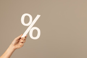 Video of hand of caucasian woman holding white percent sign with copy space against grey background