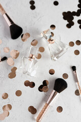 A flatlay of empty perfume bottles, makeup brushes, and rose gol © Cavan
