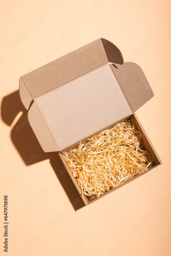 Poster vertical image of open box with straw lining and copy space over cream background