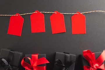 Draagtas Red gift tags on pegs and black gift boxes with copy space over black background © vectorfusionart