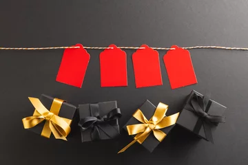 Muurstickers Red gift tags on pegs and black gift boxes with copy space over black background © vectorfusionart