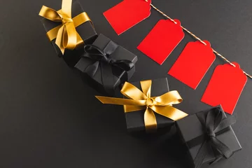 Foto op Plexiglas Red gift tags on pegs and black gift boxes with copy space over black background © vectorfusionart