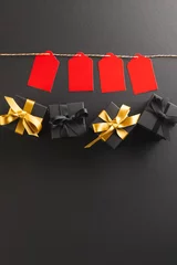 Keuken foto achterwand Vertical image of red gift tags on pegs and black gift boxes with copy space over black background © vectorfusionart