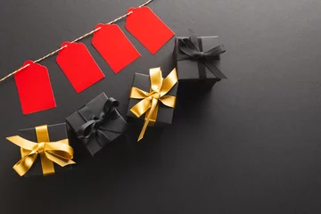 Fotobehang Red gift tags on pegs and black gift boxes with copy space over black background © vectorfusionart