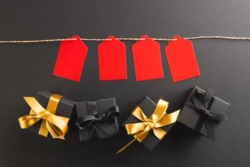 Keuken foto achterwand Red gift tags on pegs and black gift boxes with copy space over black background © vectorfusionart