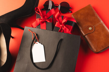 Gift bag, gift boxes, shoes, wallet, sunglasses and copy space over red background