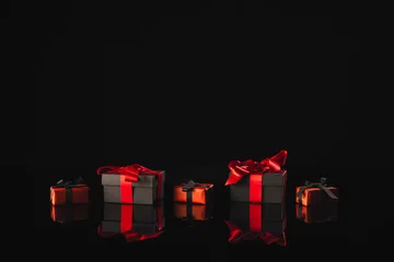 Poster Black and red gift boxes with ribbon and copy space over black background © vectorfusionart