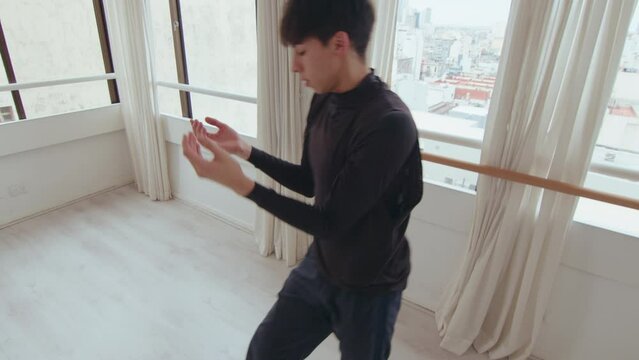Young expressive male performer improvising during contemporary dance practice at the studio. High angle view, zoom shot
