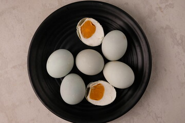 telur Asin is salted duck eggs. telur Asin are eggs made by soaking duck eggs in a salt solution. Indonesian food. served on black plate on gray marble table.