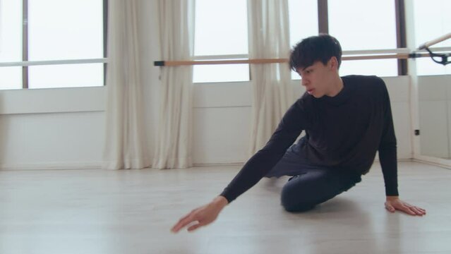 Young talented male dancer performing expressive and graceful elements while practicing modern dance elements on a rehearsal at the studio. Zoom shot