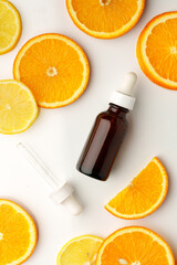 Glass bottle of essential citrus oil on oranges background
