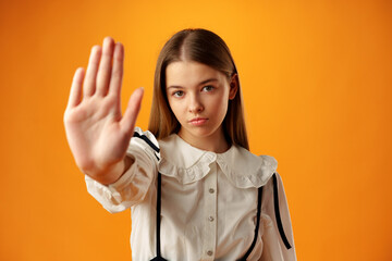 Teen girl extend hand in block gesture against yellow background