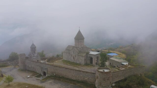 Forward reveal drone footage of Tatev Monastery on foggy autumn morning. Tatev, Syunik Province, Armenia.