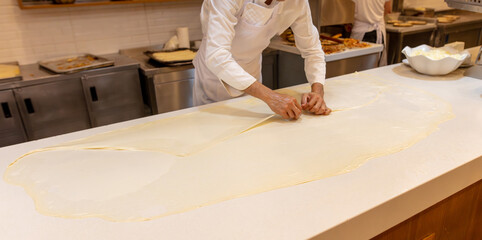 The cook rolls out the dough in the kitchen