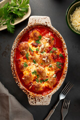 Meat balls in tomato sauce with mozzarella cheese and parmesan on a dark background top view vertical photo