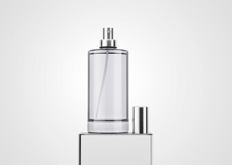 Plain blank round cylindrical branding glass bottle of perfume with metallic sliver cap lid placed on glass cube block