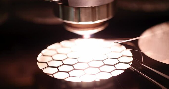 Programmed laser machine cuts geometric shaped cells from solid material in dark studio. Concept of industry and welding production in unlit factory