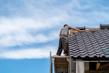 covering the tip of the roof with a ceramic tile by a craftsman, copy space