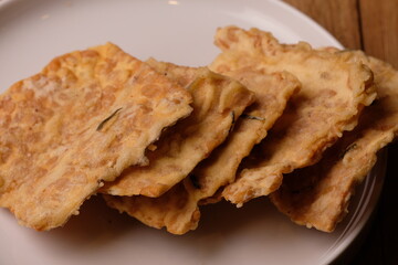 Keripik Tempe. Tempeh Chips is a typical Indonesian snack made from thinly sliced tempeh then fried with rice flour, coconut milk, and spices. Indonesian food. served on a white ceramic plate. Kripik.