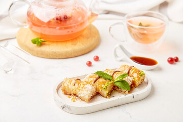 Glass teapot of natural healthy berry tea and traditional turkish baklava with honey and mint- aesthetic table setting . Copy space