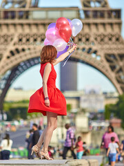 Woman charming girl playing with many colorful balloons. Summer in Paris celebration happiness and lifestyle.
