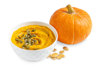 Homemade creamy healthy vegetarian pumpkin soup made of pureed vegetables of orange colour decorated with dried peeled seeds served in bowl isolated on white background with vegetable ingredient