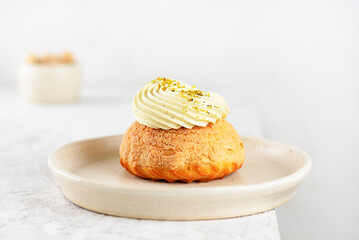 Choux cake with pistachio cream, French dessert shu on a table.