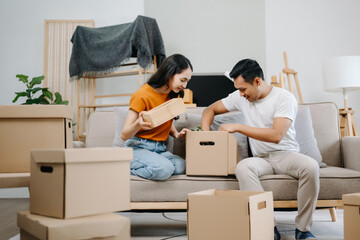 Fototapeta na wymiar Young couple with big boxes moving into a new house, new apartment for couple, young asian man and woman helping to lift boxes on sofa for the new home, Moving house..