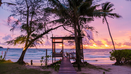 Romantic dinner on the beach in Koh Kood Thailand, woman watching sunset during dinner on the beach with a wooden pier and private patio on a luxury vacation in Thailand