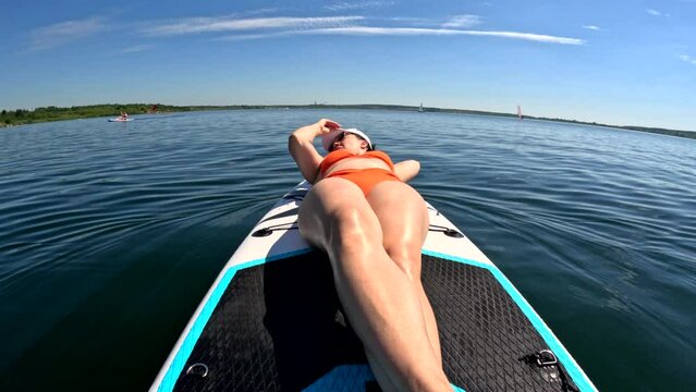 woman sunbathing while floating on supboard