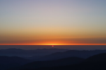 dawn in the mountains, the sun appears on the horizon, the first rays, dark mountains
