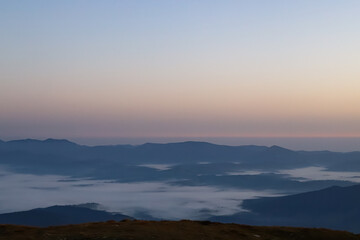Obraz premium clouds spread across the valleys between the mountain peaks before dawn