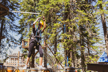 Adventure park fun, child girl with protective gear  pass barriers at summer camp.