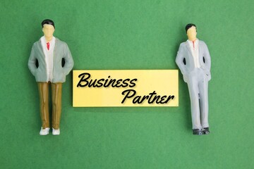 two miniature people and colored paper with the word business partner. businessmen partnership concept