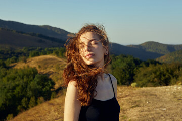 portrait of a happy woman in the mountains, with her hair blown by the wind on a sunny day